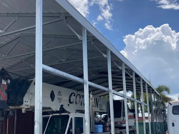 Two Gordon Crane machines parked under a steel canopy at the yard in North Fort Myers, red and white paint and black GORDON lettering along the booms.